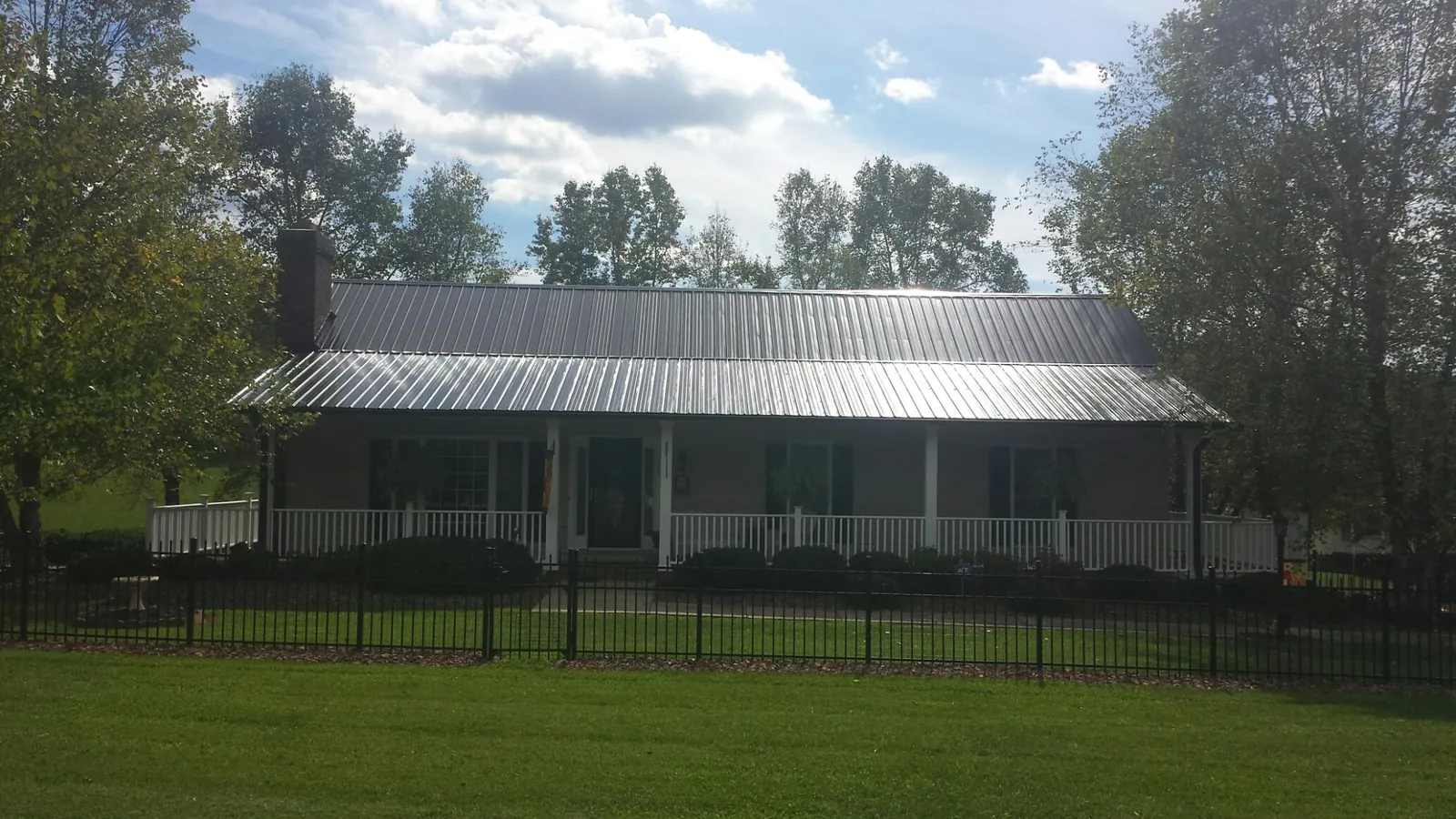Gray metal roof on a brick ranch with a full width front porch — Gutter Guard Installation work by our crew in Florence